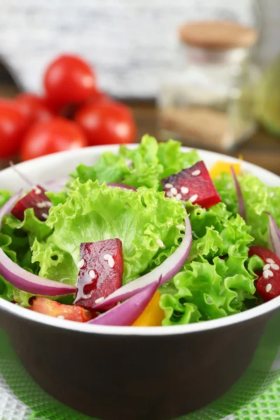 Bowl of fresh green salad on table with napkin, closeup — Stock Photo, Image