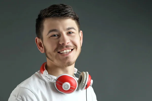 Handsome young man with headphones on grey background — Stock Photo, Image