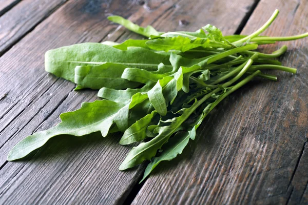 Green arugula leaves on wooden table — Stock Photo, Image