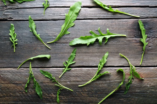 Grüne Rucolablätter auf Holztisch — Stockfoto