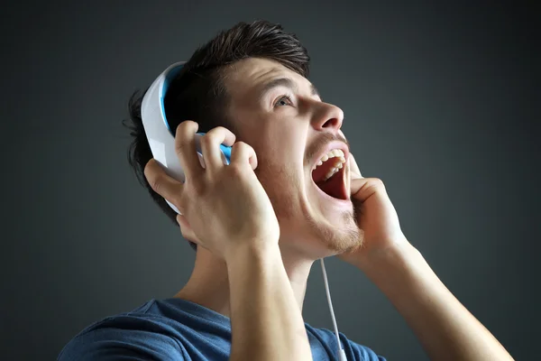 Joven guapo escuchando música sobre fondo gris —  Fotos de Stock