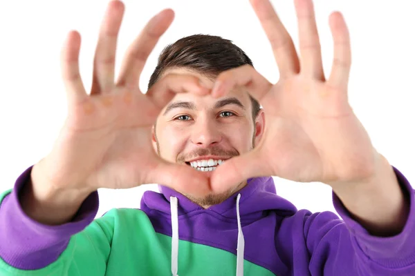 Usmívající se atraktivní mladý muž dělá srdce pomocí prstů — Stock fotografie
