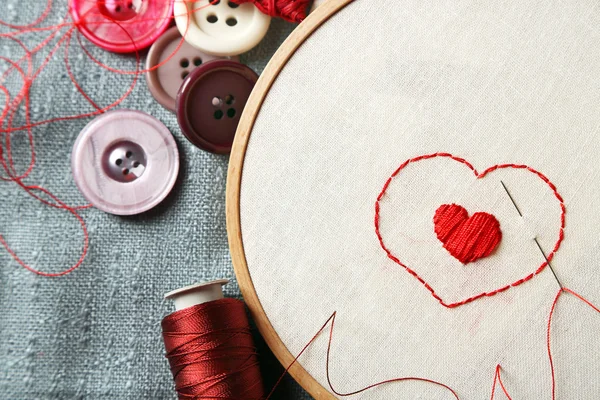 El aro de bordado con tela e hilos de coser rojos en la mesa de cerca —  Fotos de Stock