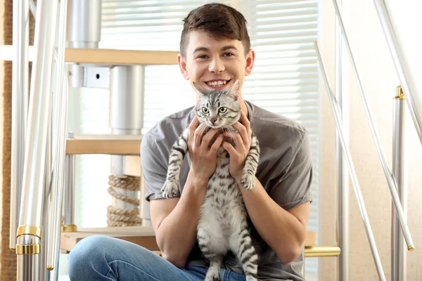 잘생긴 젊은 남자 집에서 단계에 앉아 귀여운 고양이 함께 — 스톡 사진