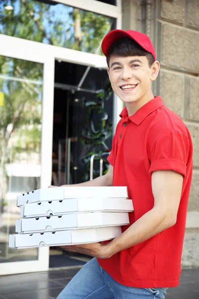 Joven entregando caja de pizza cerca de casa —  Fotos de Stock