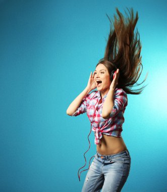 Young woman with headphones on turquoise background clipart