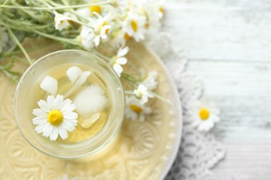 soğuk papatya çayı buz küpleri ve renk ahşap arka plan üzerinde papatya çiçeği ile bardak