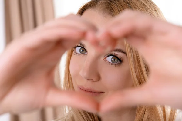 Lächelnde attraktive junge Frau macht Herz mit Fingern — Stockfoto