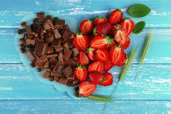 Strawberry with chocolate in shape of heart on color wooden background — Stock Photo, Image