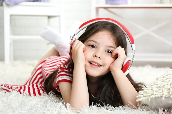 Beautiful little girl listening to music in room — Stock Photo, Image