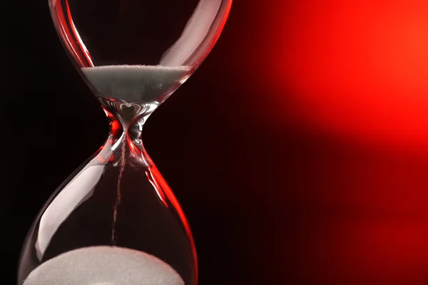 Hourglass on dark red background — Stock Photo, Image