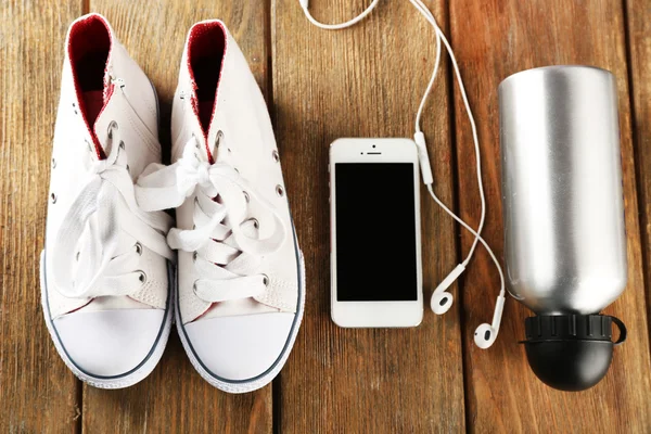 Zapatillas y auriculares en mesa de madera, vista superior —  Fotos de Stock