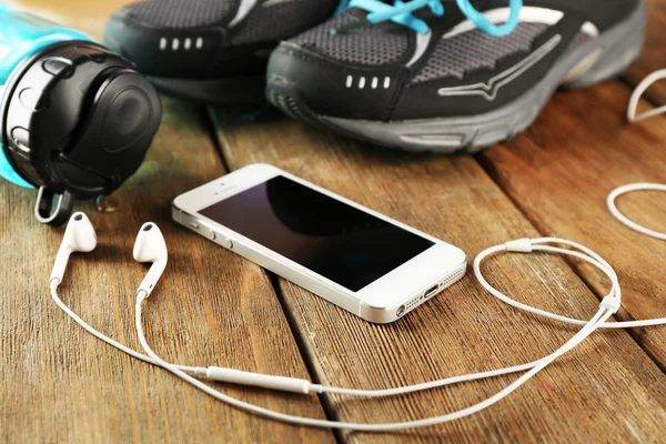 Sneakers and earphones on wooden table, closeup — Stock Photo, Image