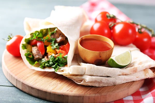 Burrito saboroso caseiro com legumes, batatas fritas na placa de corte, no fundo de madeira — Fotografia de Stock
