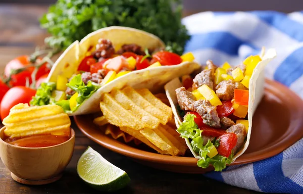 Burritos caseros de ternera con verduras, papas fritas en plato, sobre fondo de madera — Foto de Stock