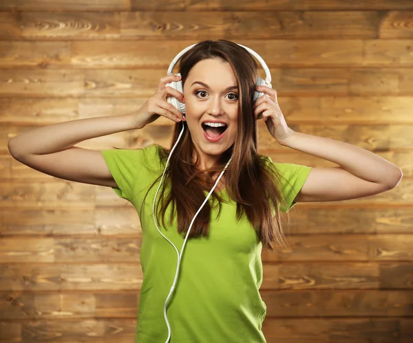 Young woman with headphones on wooden background — Stock Photo, Image