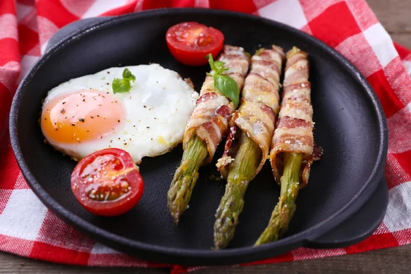 Piatto di asparagi con uova e pancetta in padella sul tavolo, primo piano — Foto Stock