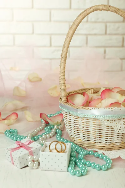 Hochzeitskorb mit Rosenblättern auf dem Tisch, auf hellem Hintergrund — Stockfoto