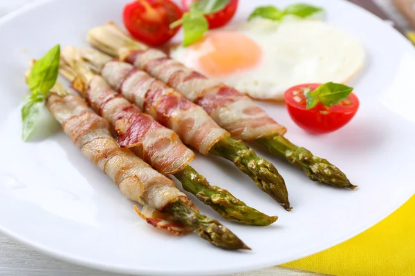 Prato de espargos com bacon e ovo em prato na mesa, close-up — Fotografia de Stock