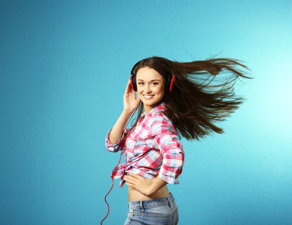 Young woman with headphones on turquoise background — Stock Photo, Image