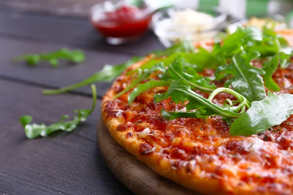 Pizza con rúcula sobre mesa de madera — Foto de Stock