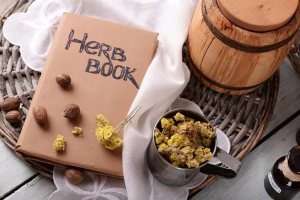 Dried herb with nutmeg and book — Stock Photo, Image