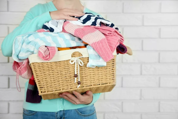 Woman holding basket with heap of different clothes — Stock Photo, Image