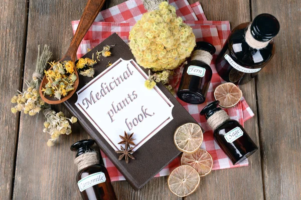 Medicinal plants book with dried herbs and bottles — Stock Photo, Image