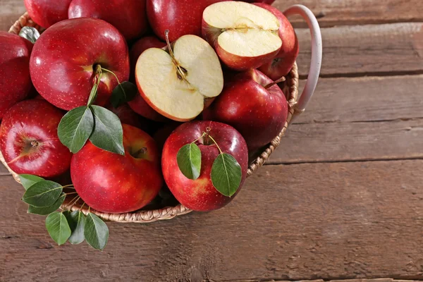 Красное яблоко в плетеной корзине на деревянном столе, вид сверху — стоковое фото