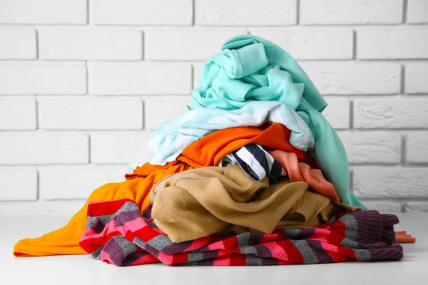 Heap of different clothes on wooden table — Stock Photo, Image