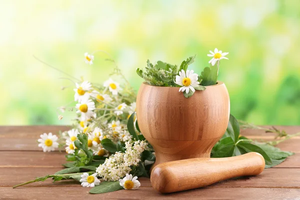 Herbs and flowers with mortar, on wooden table — Stock Photo, Image