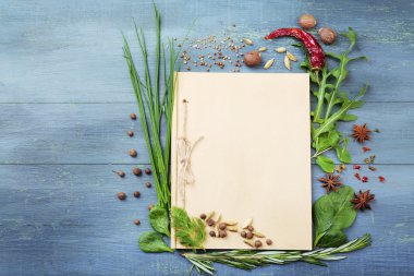 ahşap arka plan üzerinde taze otlar ve baharatlar ile açık tarif kitabı