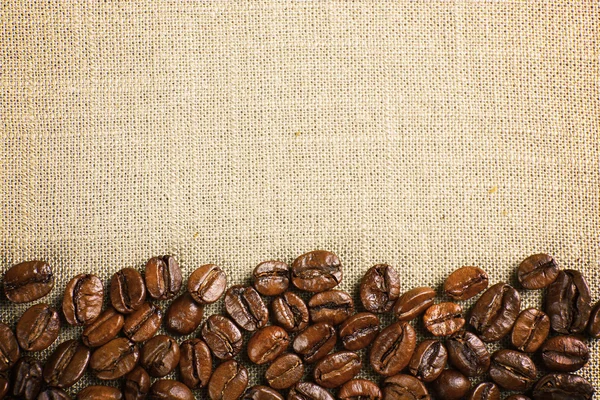 Frame of coffee beans on color sackcloth — Stock Photo, Image