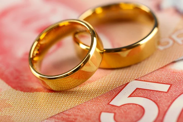 Golden wedding rings on banknotes background. — Stock Photo, Image