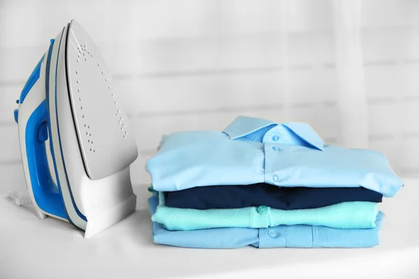 Pile of clothes and electric iron — Stock Photo, Image