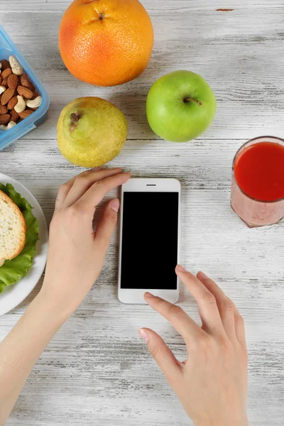 Mat och mobiltelefon i kvinnliga händer — Stockfoto