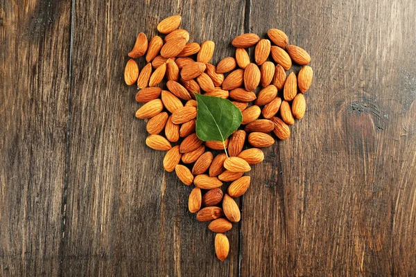 Almendras dispuestas en forma de corazón con hoja verde — Foto de Stock