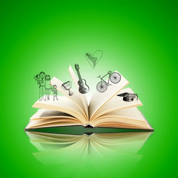 Open book with drawings on green background — Stock Photo, Image