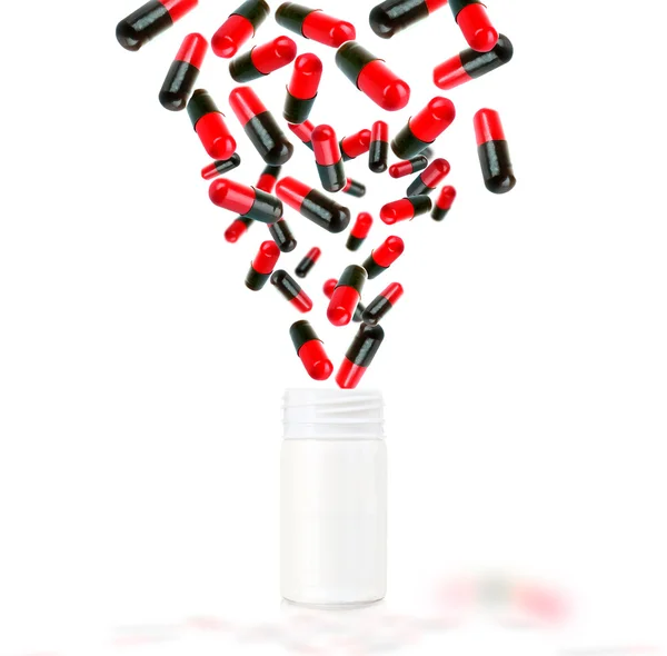 Heldere kleur pillen vliegen uit de buurt van open plastic fles geïsoleerd op wit — Stockfoto