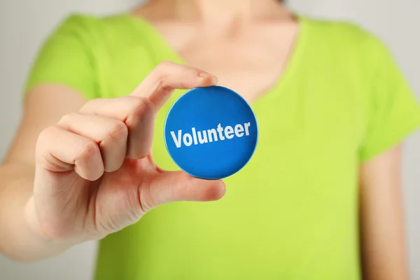 Botón de voluntario redondo en mano de chica aislada en blanco — Foto de Stock