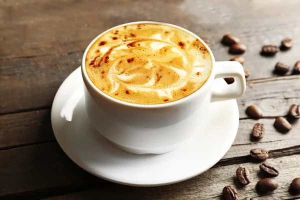 Cup of coffee latte art with grains and chocolate on wooden background — Stock Photo, Image