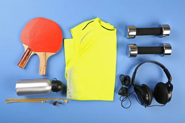 Sportgeräte und T-Shirt auf Farbtisch, Ansicht von oben — Stockfoto