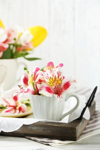 Lindas flores na xícara, no fundo de madeira — Fotografia de Stock
