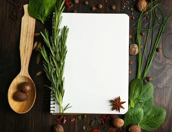 Libro de recetas abierto con hierbas frescas y especias sobre fondo de madera —  Fotos de Stock