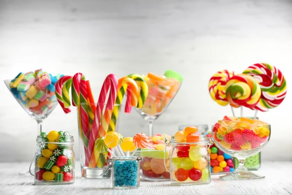 Colorful candies in jars on table on wooden background — Stock Photo, Image