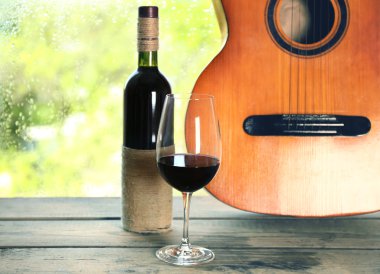 Sonraki pencere yağmur damlaları ile akustik gitar ve bardak şarap