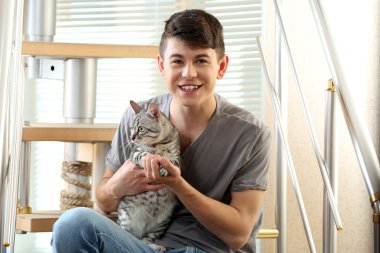 yakışıklı delikanlı ile evde basamaklarında oturan sevimli kedi