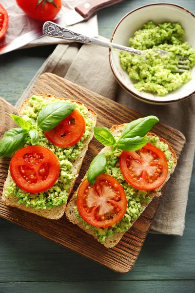 Vegansk smörgås med avokado och grönsaker på skärbräda, på trä bakgrund — Stockfoto