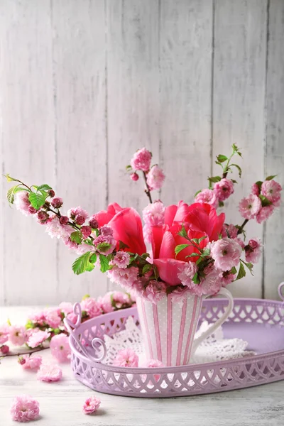 Ramo de primavera en taza de colores sobre fondo de madera de color — Foto de Stock