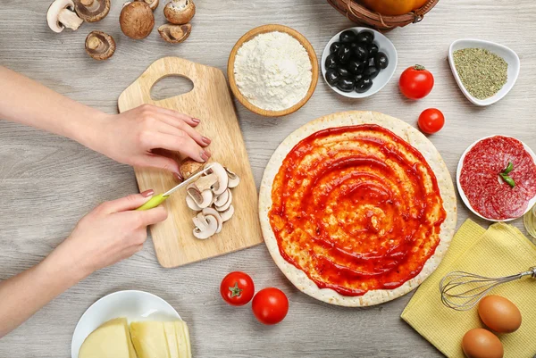 Žena ruce vaření pizza na dřevěný stůl, detail — Stock fotografie